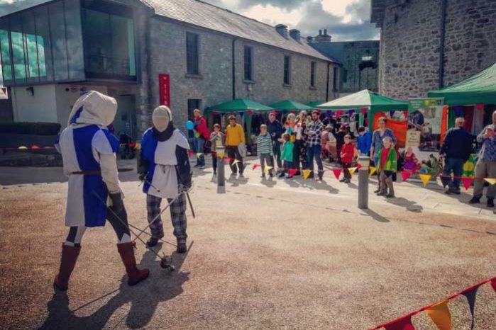 Onlookers are entertained by three fighters dressed in full medieval costume taking part in a sword fight as part of our Annual Medieval Fair at Athlone Castle courtyard.