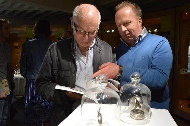 Two men visiting the temporary “Treasures in Time” exhibition at Athlone Castle Visitor Centre. They gaze through the exhibition catalogue as they find the treasures within the exhibition.